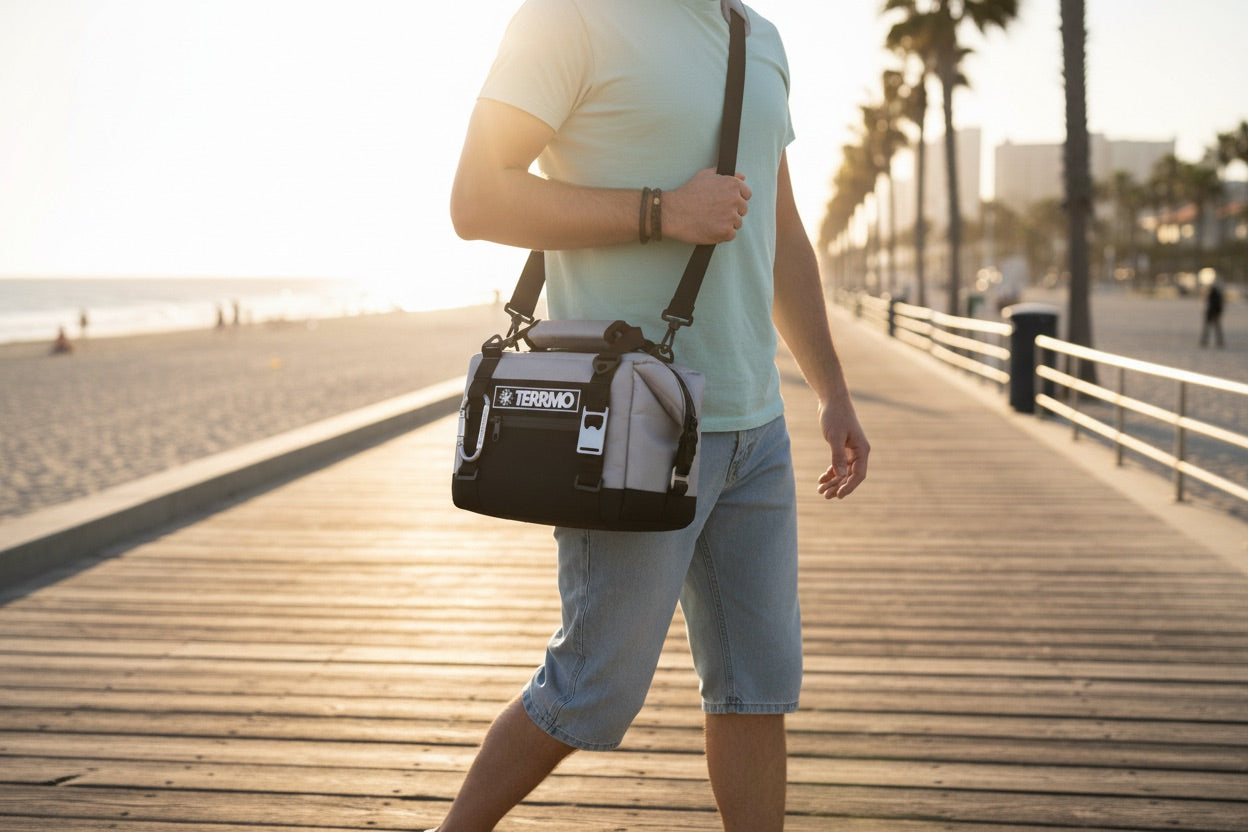 Eine Person hält eine kleine Strandkühltasche der Marke TERRMO EPIC 5 in der Nähe eines Ufers.